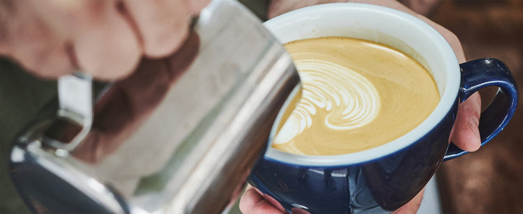 A latte being poured by a barista